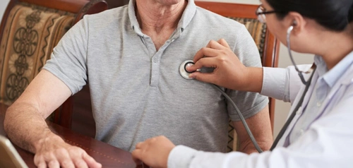 GP examining patient’s chest with a stethoscope