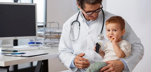 Father holding his baby while a pediatric doctor at Harpley Doctors conducts a routine child health checkup